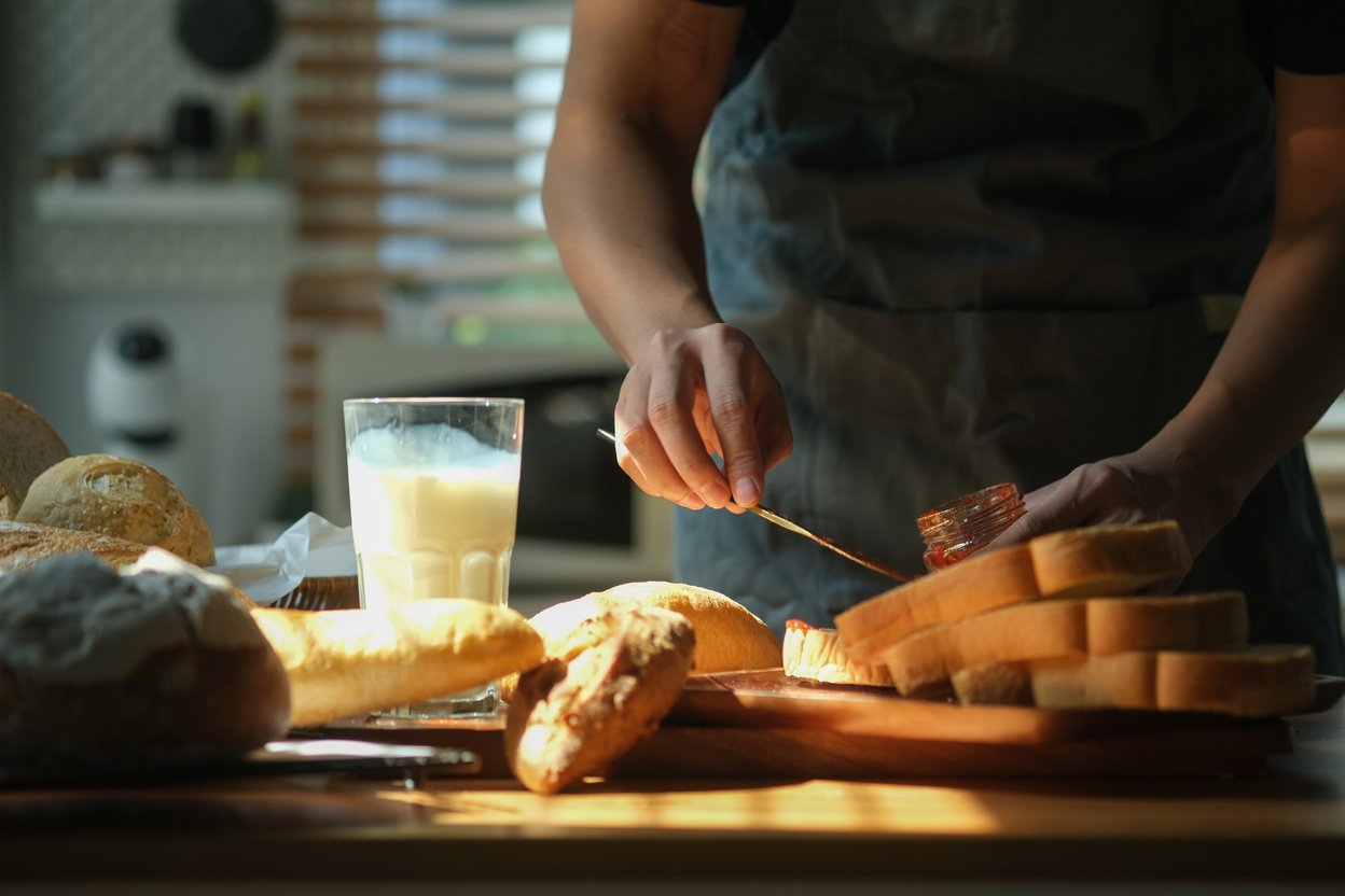 Man is preparing breakfast, spreading homemade strawberry jam on